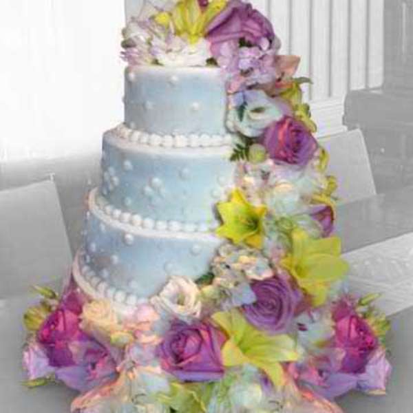 Three-tier blue cake with cascading pastel flowers