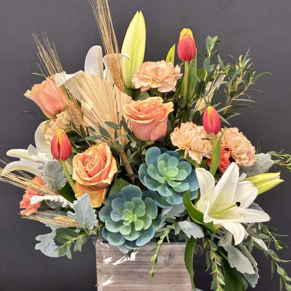 Mixed bouquet with roses, tulips, lilies, and succulents in a wooden box