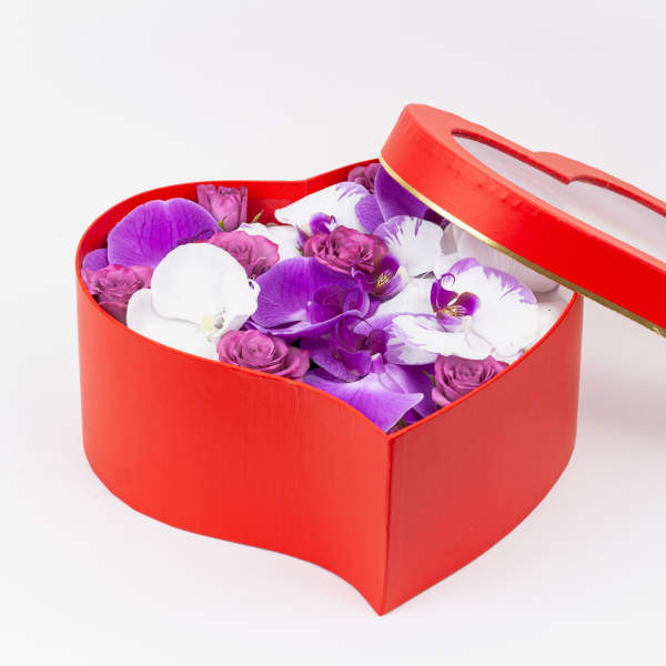 Heart-shaped red box filled with purple and white orchids and small roses