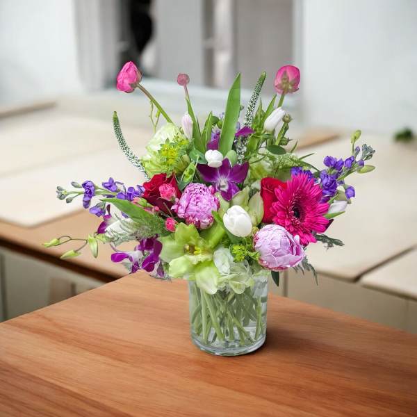 Mixed pink, purple, and white flower arrangement in a clear glass vase