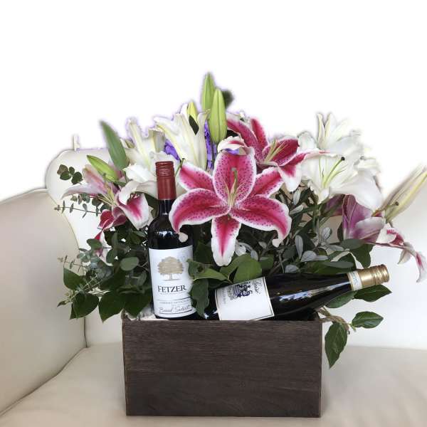 Flower arrangement in a wooden box with two wine bottles