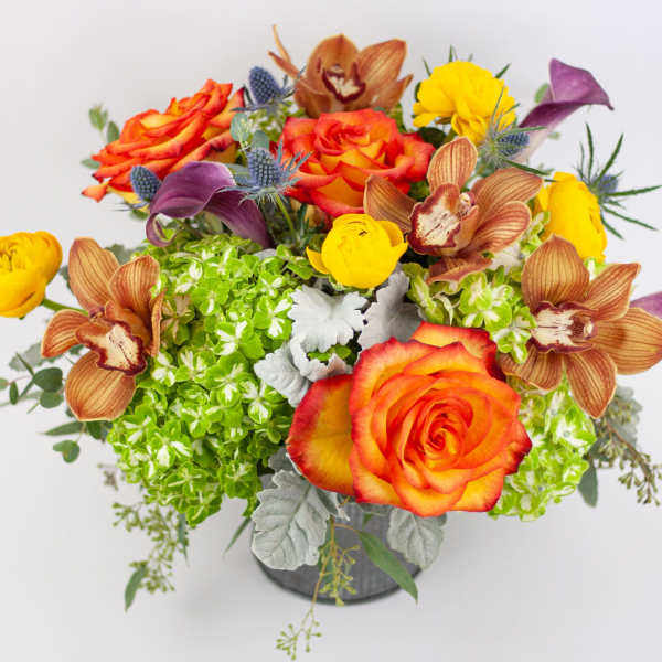 Colorful bouquet of roses, orchids, and yellow blooms in a vase