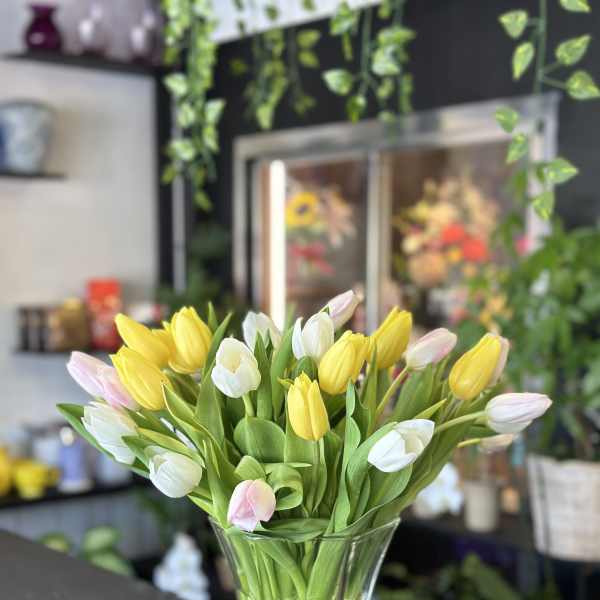 Bouquet of yellow, white, and pink tulips in a clear glass vase