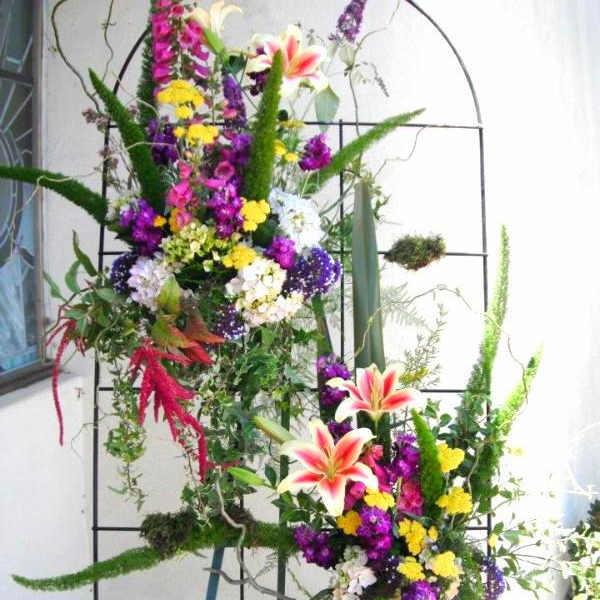 Tall floral standing arrangement with lilies and mixed blooms on a metal frame