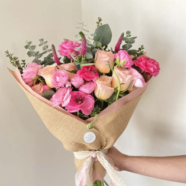 Pink and peach mixed bouquet wrapped in burlap with a ribbon
