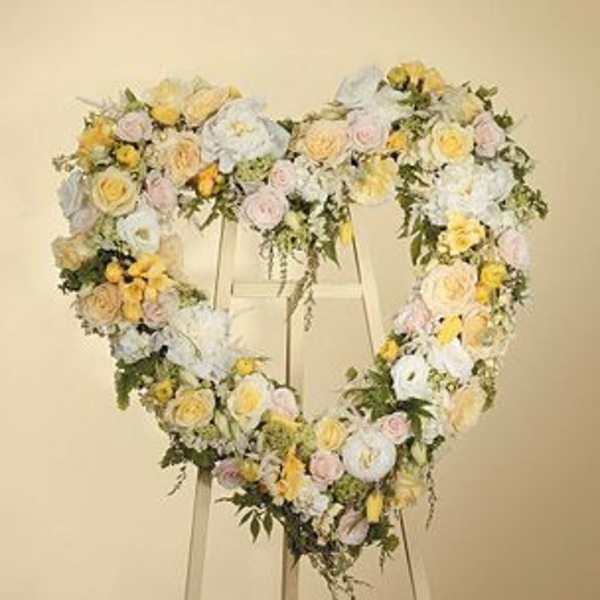 Heart-shaped floral wreath on an easel with pastel roses and white blooms