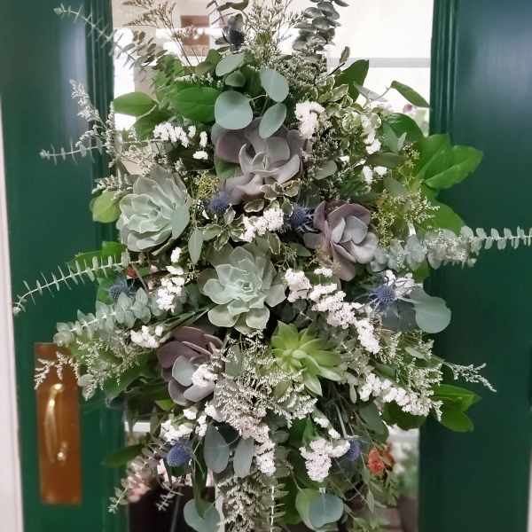 Tall green and white floral arrangement with succulents and eucalyptus