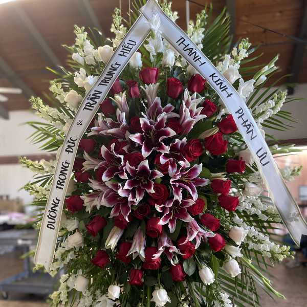 Large funeral wreath of red roses and white lilies with condolence ribbons