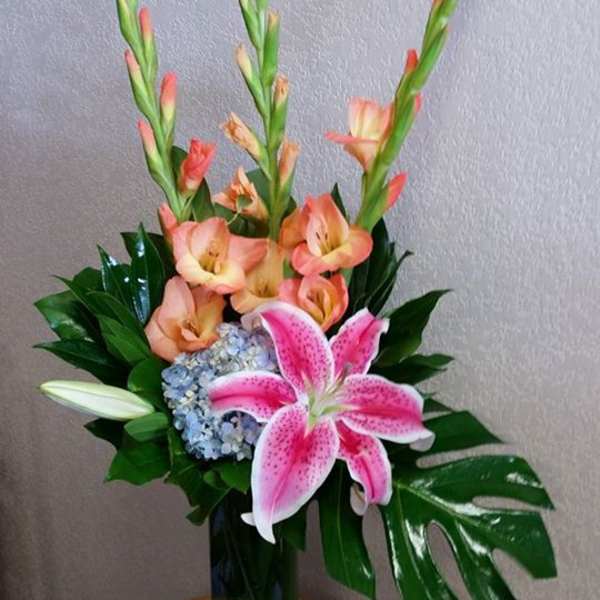 Pink lily and peach gladiolus arrangement in a blue vase