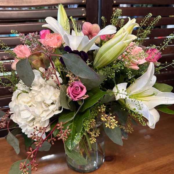Bouquet of white lilies, pink roses, and white hydrangea in a glass vase