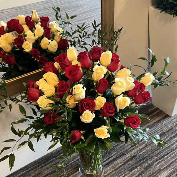 Bouquets of red and yellow roses in a glass vase