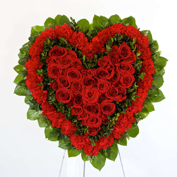 Heart-shaped red rose and carnation arrangement on a stand