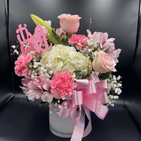 Pink and white flower arrangement in a white vase with a ribbon bow