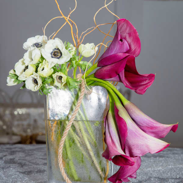 White anemones and magenta calla lilies in a glass vase