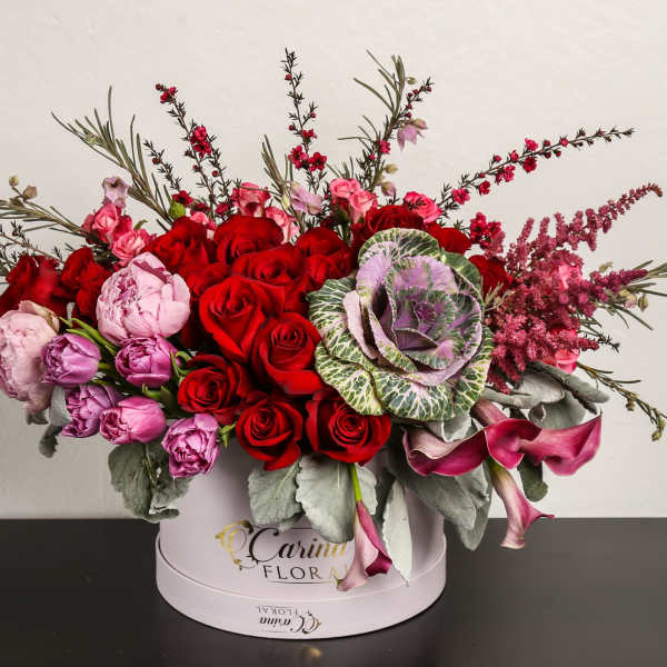 Red and pink roses with purple blooms in a round hat box