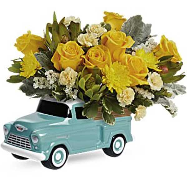 Yellow roses and white flowers arranged in a turquoise pickup truck container