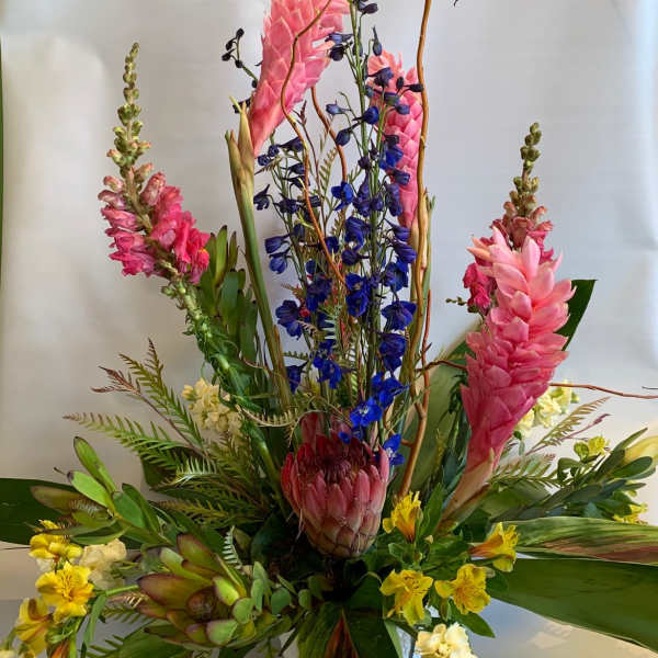 Tall tropical arrangement with pink and blue flowers in a vase