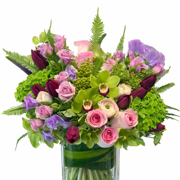 Mixed pink, purple, and green flowers arranged in a glass vase