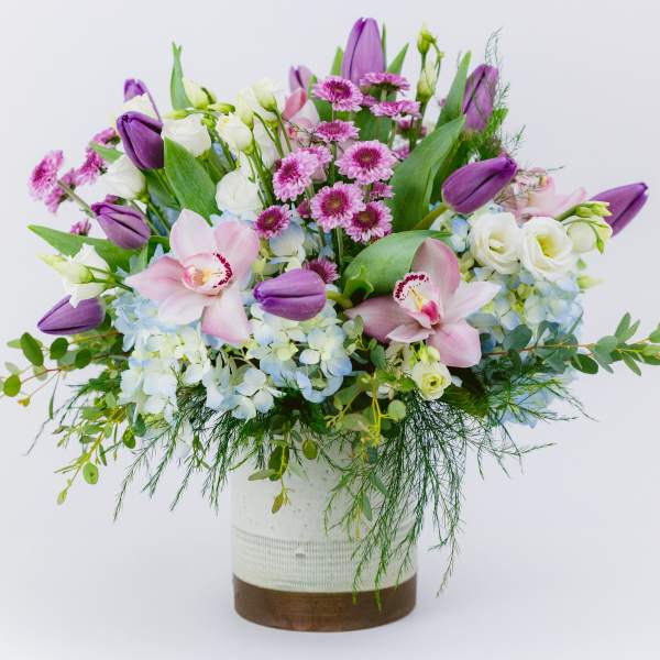 Purple tulips and pink orchids in a white vase