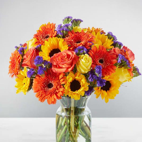 Bright mixed bouquet of gerbera daisies and roses in a glass vase