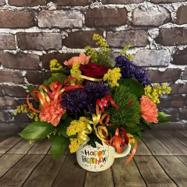 Colorful birthday flower arrangement in a mug-shaped container