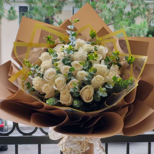 Bouquet of white roses wrapped in brown paper with a ribbon