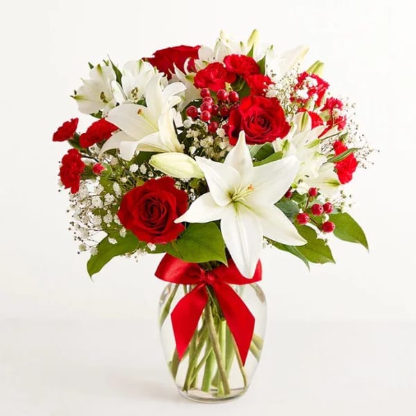 Red roses and white lilies in a glass vase with a red ribbon