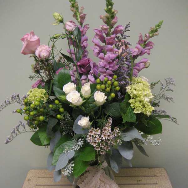 Tall bouquet of pink and white flowers in a glass vase with lace ribbon