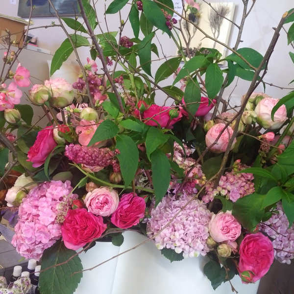 Large floral arrangement with pink roses and hydrangeas in a white container