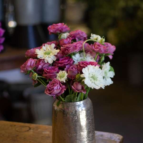 Pink roses and white daisies arranged in a silver vase