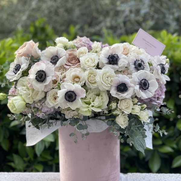 Blush and white floral arrangement in a pink hat box