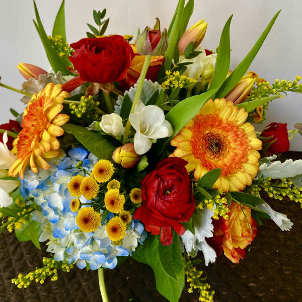 Mixed bouquet with red roses, orange gerbera daisies, and blue hydrangea