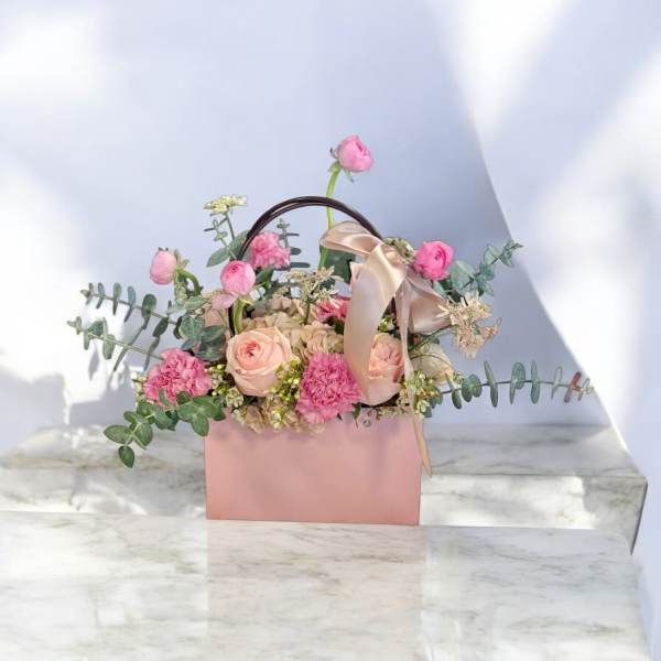 Pink floral arrangement in a blush gift box with a ribbon handle