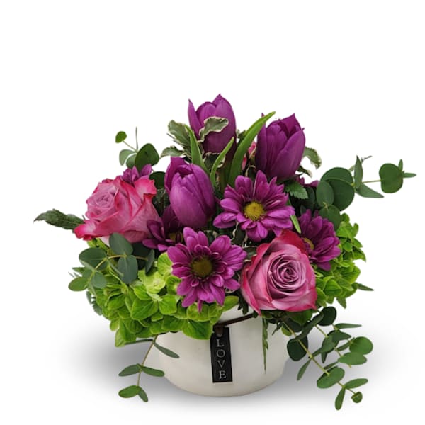 Pink and purple flowers in a white pot with a LOVE tag