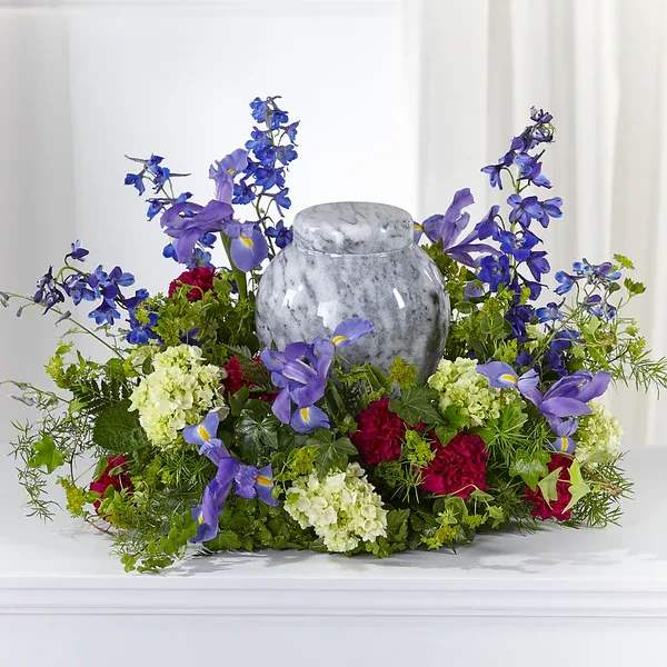 Purple and red floral arrangement around a gray urn