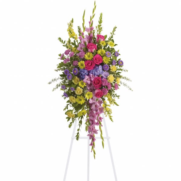 Standing floral spray with pink, purple, and yellow flowers on a white easel