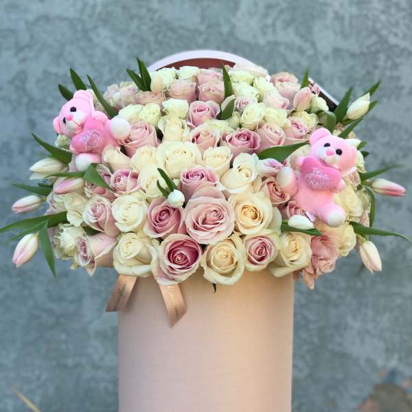 Round box of pale pink and cream roses with two pink teddy bears