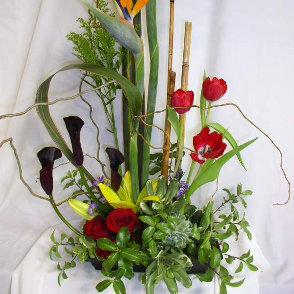 Tall tropical floral arrangement with birds of paradise, tulips, roses, and calla lilies