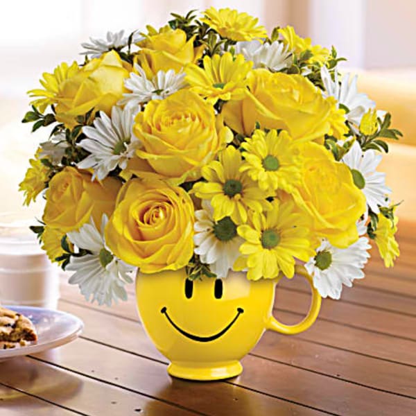 Yellow and white flower bouquet in a smiley-face mug