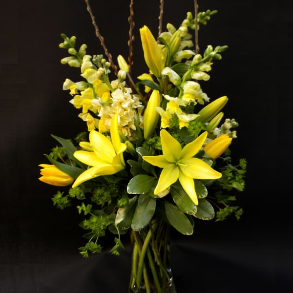 Yellow lilies and snapdragons in a clear glass vase