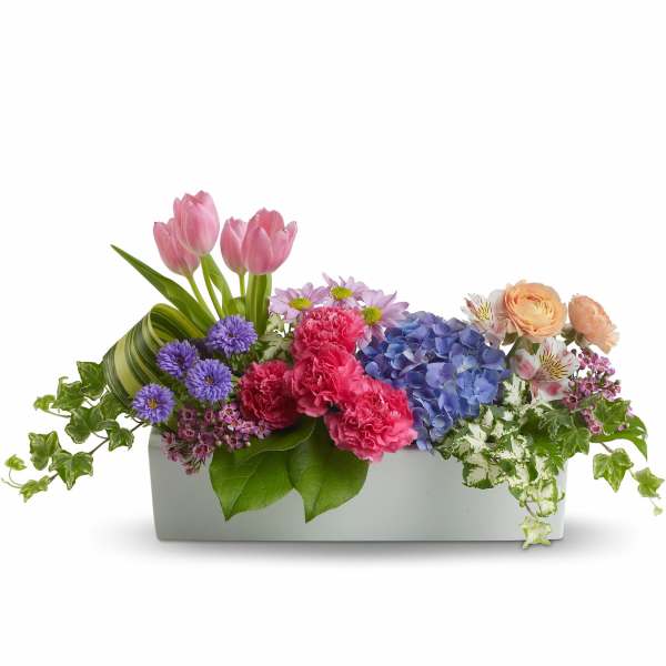 Mixed flower arrangement in a white rectangular container