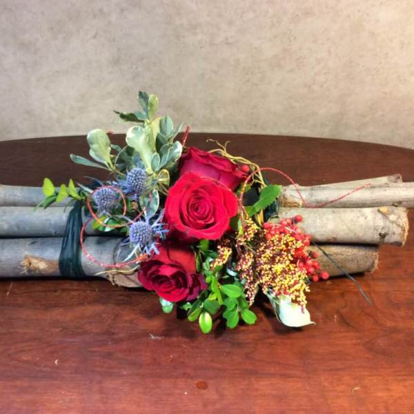 Red roses arranged with berries and greenery on bundled branches
