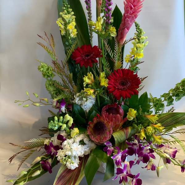 Tall tropical flower arrangement with pink ginger, red gerberas, and purple orchids
