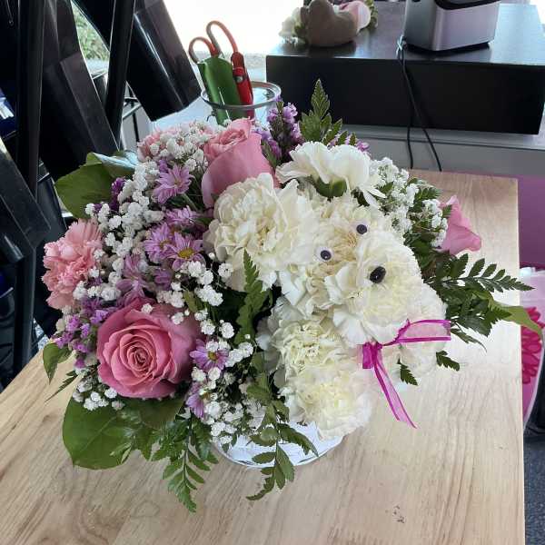 Pink and white mixed flower bouquet in a clear vase with a ribbon