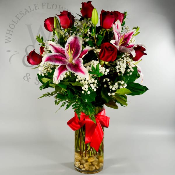 Bouquet of red roses and pink lilies in a glass vase with a red ribbon