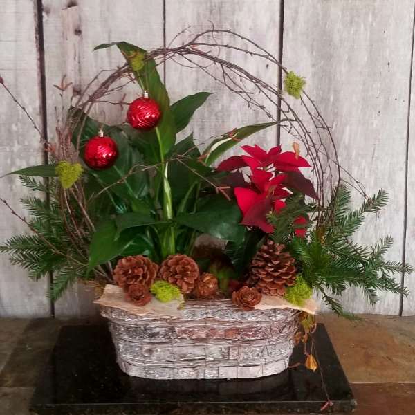 Holiday planter with red ornaments, poinsettia, and pinecones in a basket