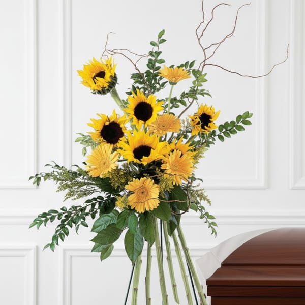 Sunflower funeral spray beside a wooden casket