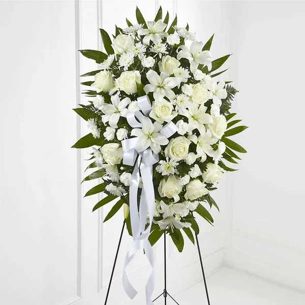 White floral standing spray on a black easel with a white ribbon