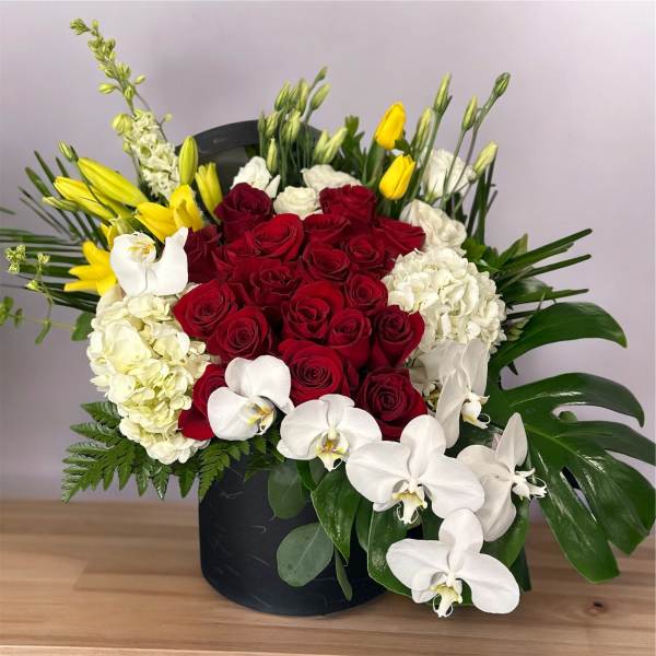 Red roses with white orchids and yellow lilies in a black box