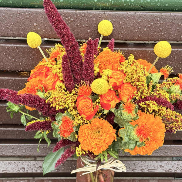 Bouquet of orange and yellow flowers in a glass jar vase